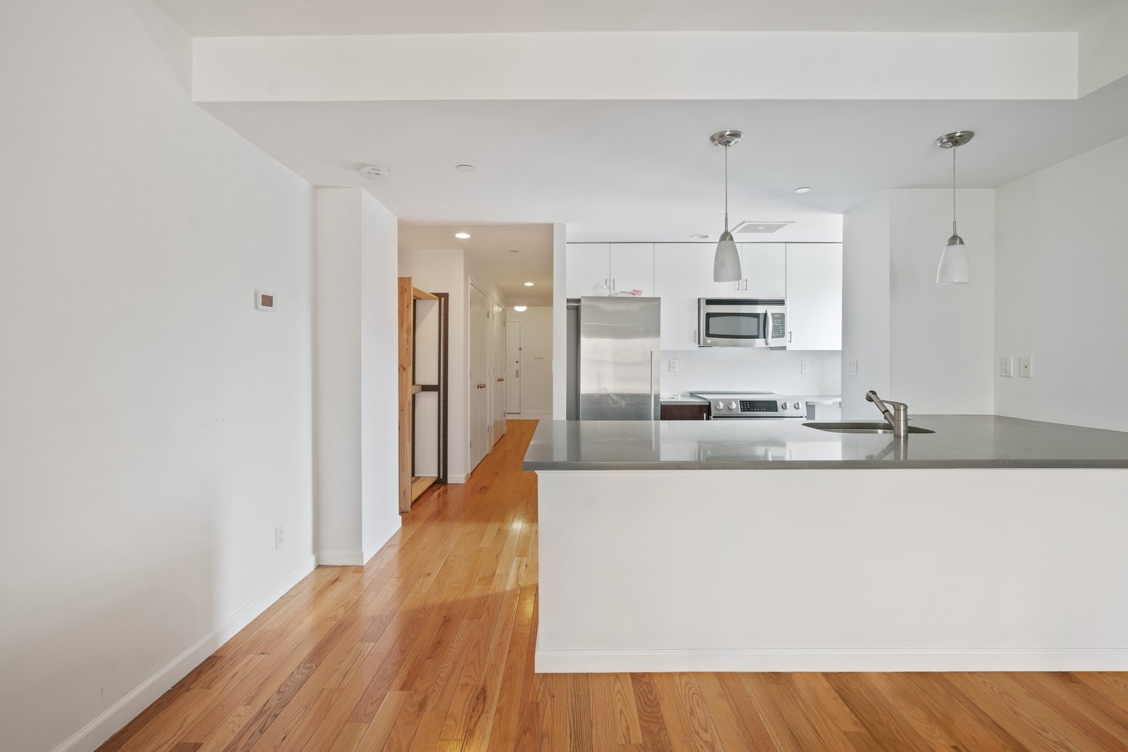 189 Avenue C, Unit 6A Manhattan, NY 10009 - Photo 2 of 10 a large white kitchen with wooden floor