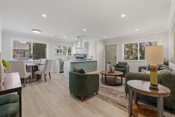 a living room with stainless steel appliances kitchen island dining table wooden floor and kitchen view