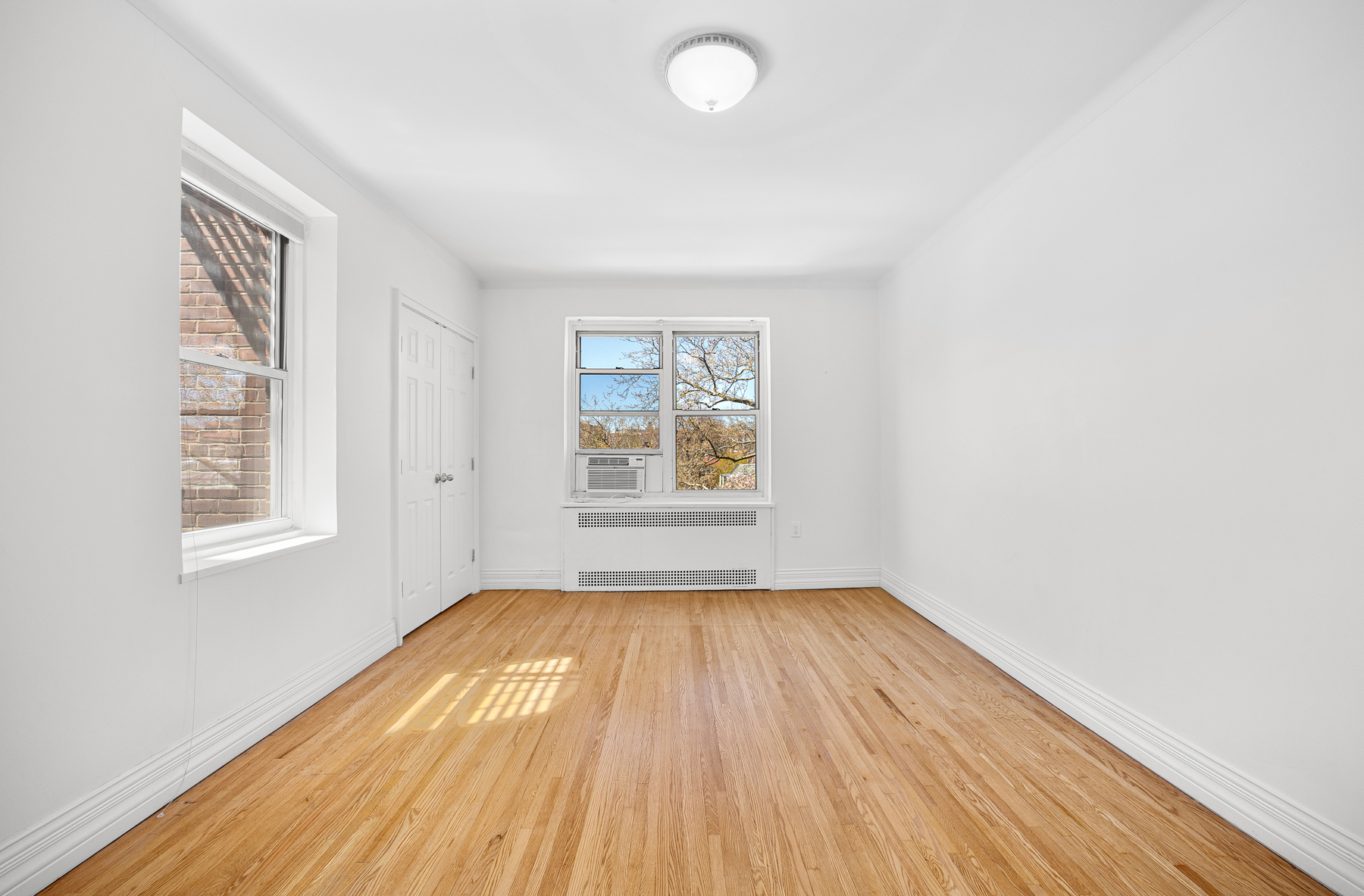 34-41 85th Street, Unit 4R Queens, NY 11372 - Photo 6 of 19 an empty room with wooden floor and windows