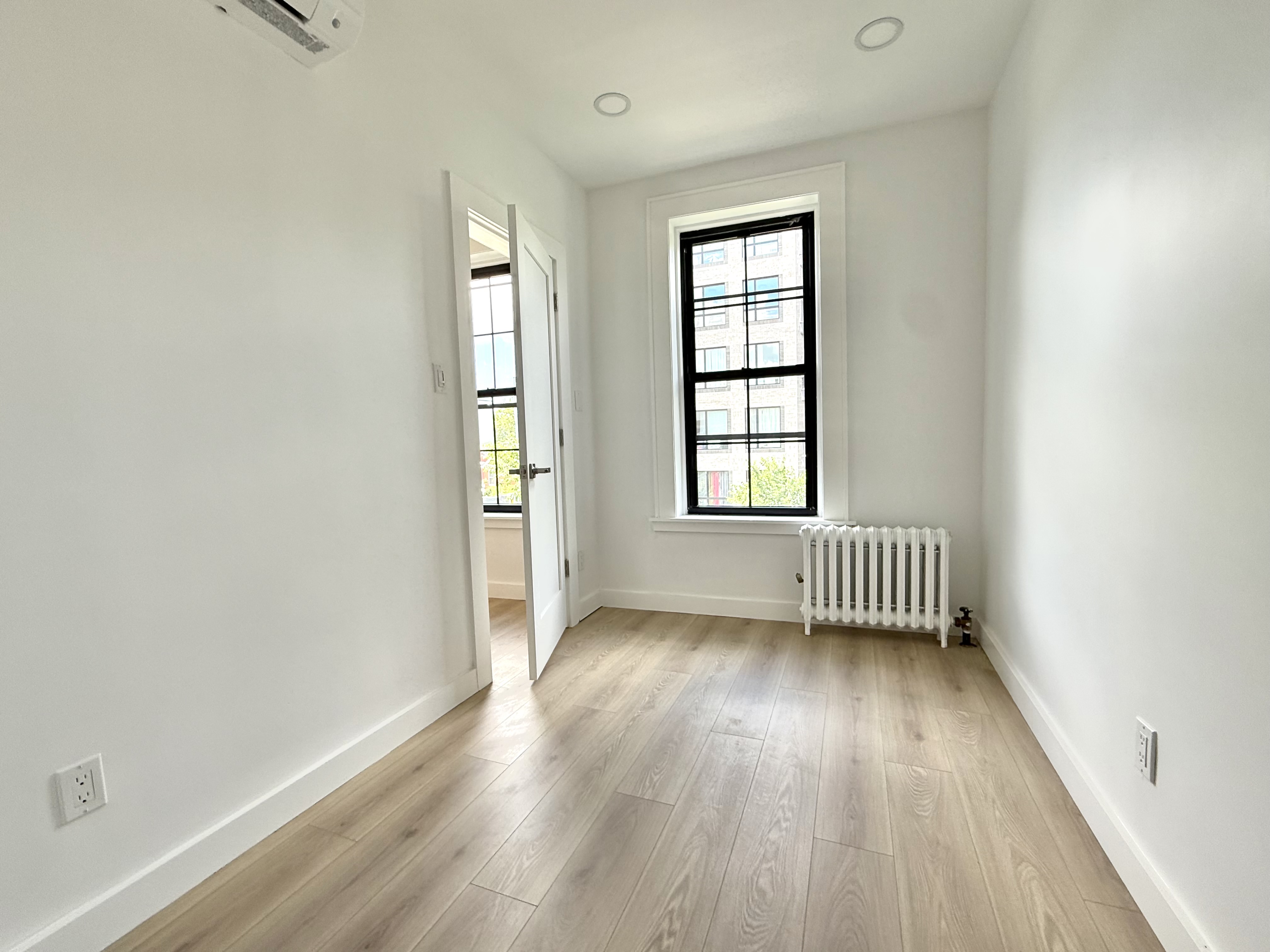 985 Rogers Avenue, Unit 3 Brooklyn, NY 11226 - Photo 5 of 10 an empty room with wooden floor and windows