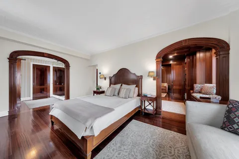 a living room with a bed and dresser with wooden floor
