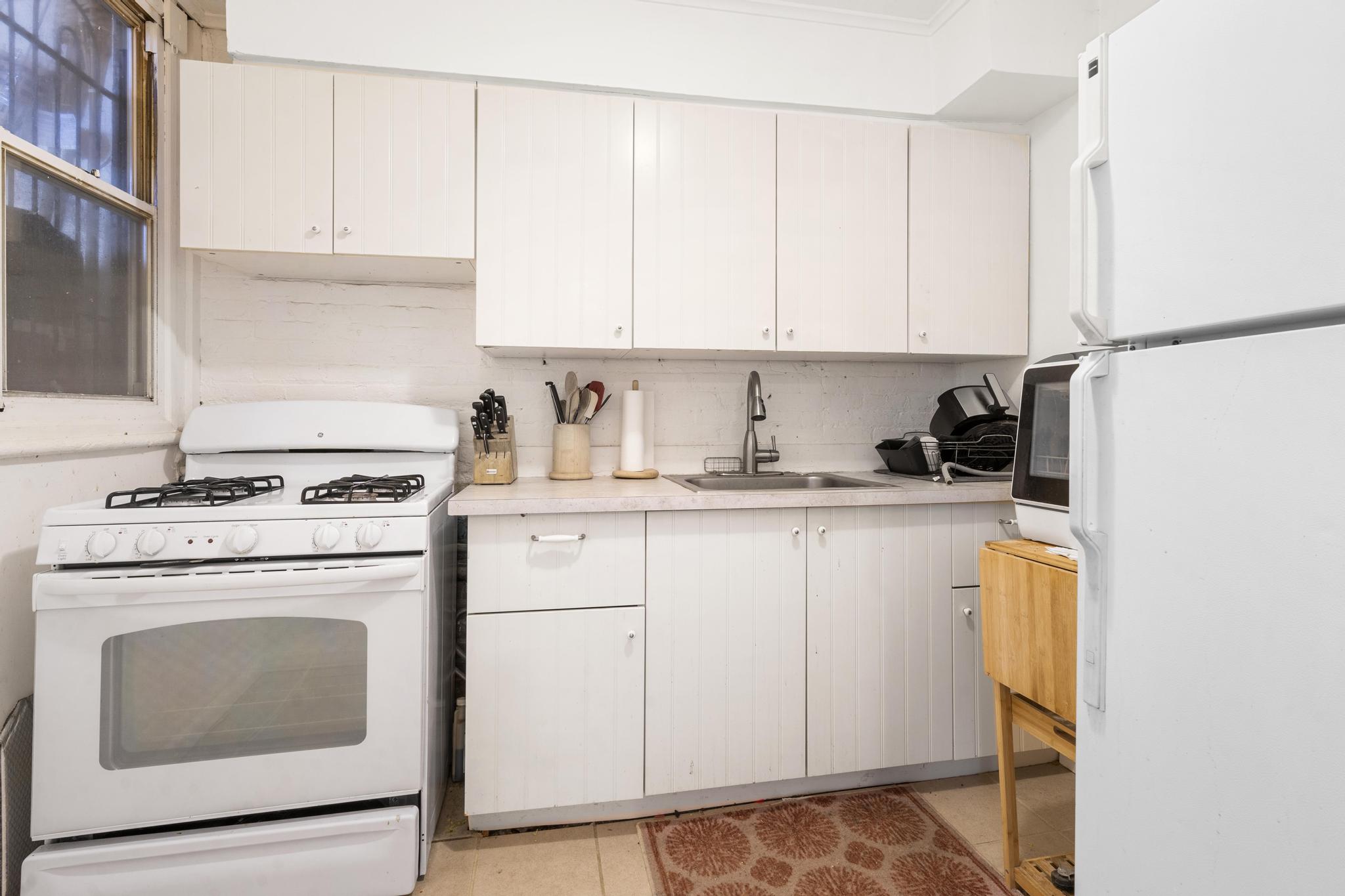 364 Clermont Avenue Brooklyn, NY 11238 - Photo 6 of 18 a kitchen with granite countertop white cabinets and white appliances