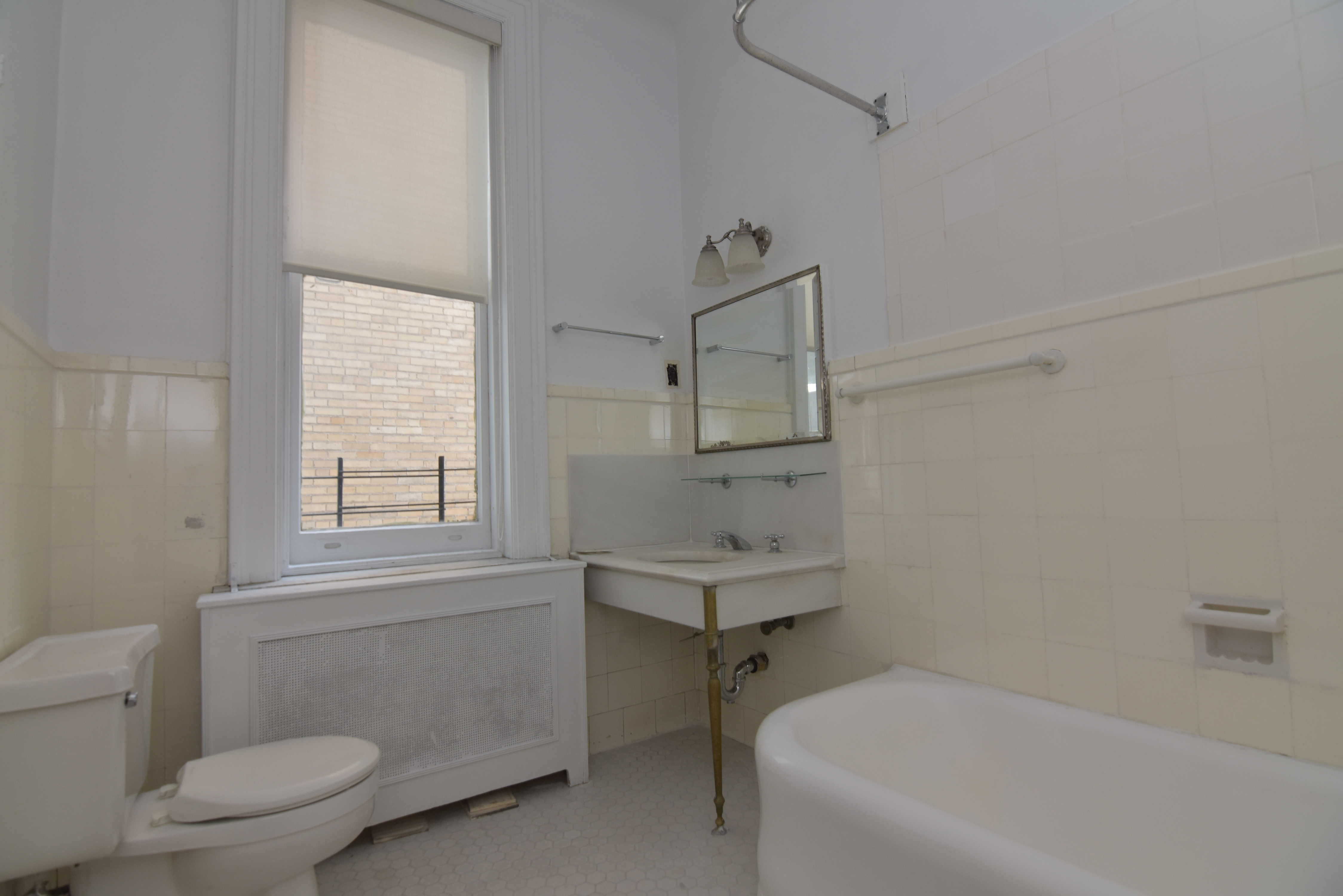 18 East 67th Street, Unit 2B/3B Manhattan, NY 10065 - Photo 15 of 18 a bathroom with a toilet a sink a mirror and a window