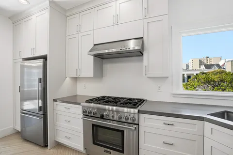 a kitchen with stainless steel appliances granite countertop white cabinets and a stove