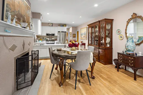 a kitchen with stainless steel appliances kitchen island granite countertop a dining table chairs and a refrigerator