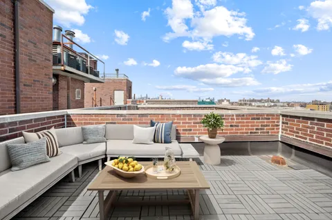 a view of a roof deck with couches and potted plants