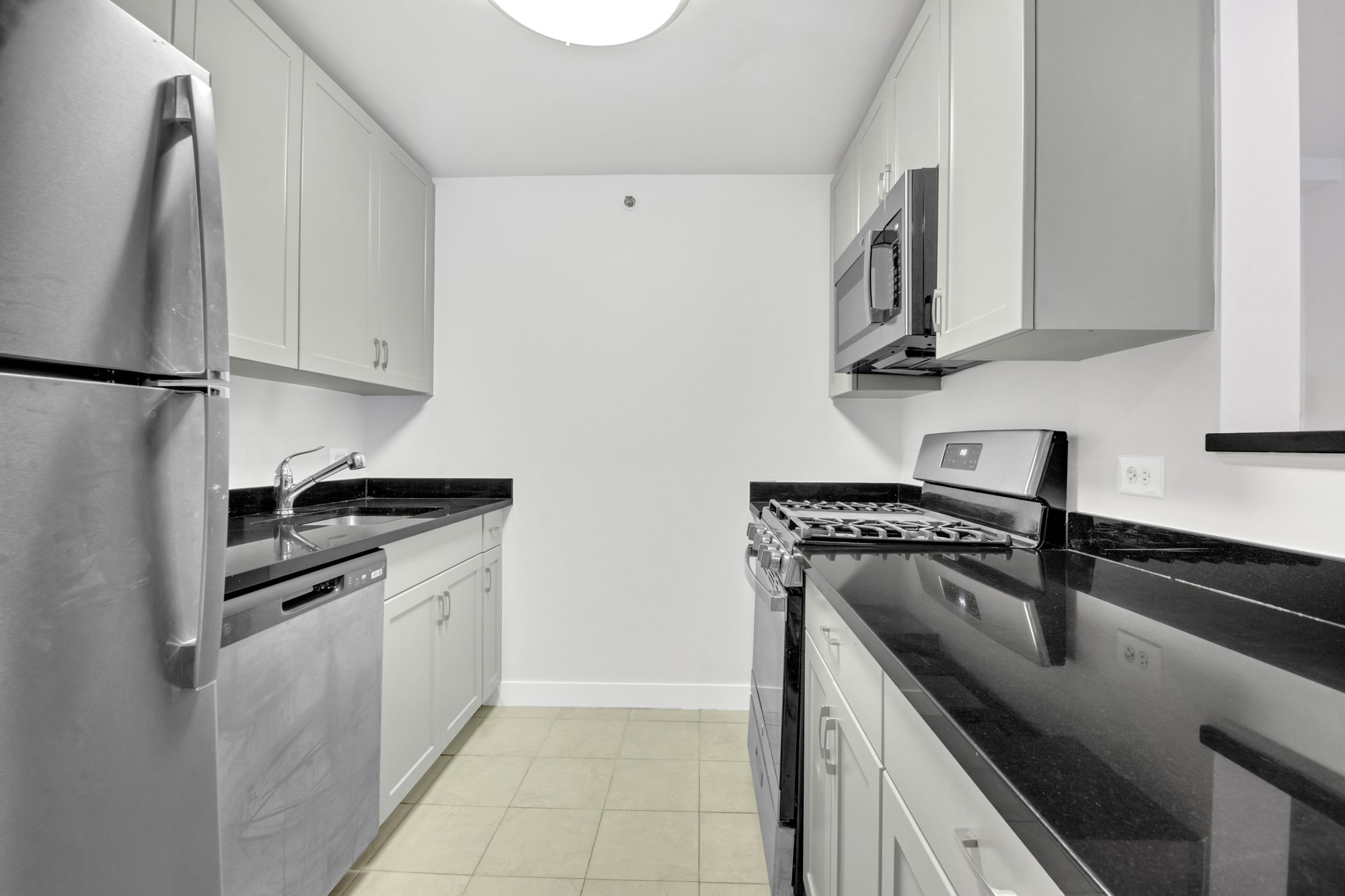 40 West 116th Street, Unit B205 Manhattan, NY 10026 - Photo 4 of 24 a kitchen with stainless steel appliances granite countertop a sink stove and refrigerator