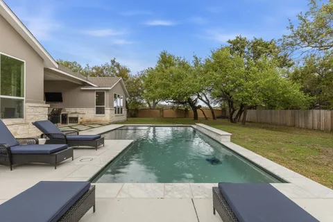 a view of a house with pool lawn chairs and wooden floor