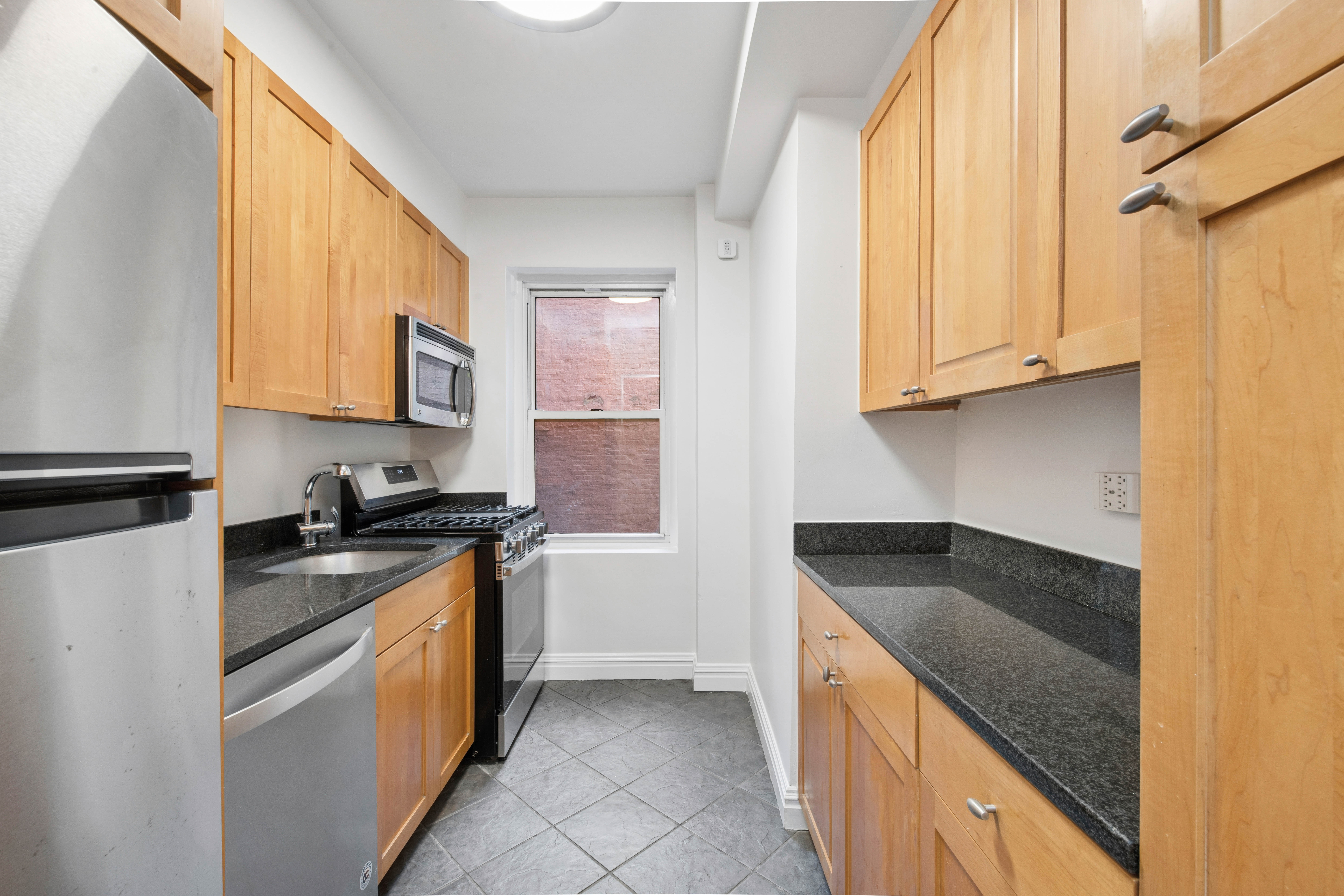 177 East 77th Street, Unit 5D Manhattan, NY 10075 - Photo 8 of 13 a kitchen with stainless steel appliances granite countertop a sink and a stove