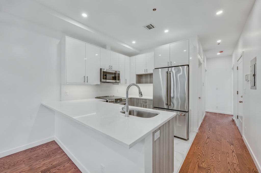 109 President Street, Unit 3 Brooklyn, NY 11231 - Photo 5 of 18 a kitchen with stainless steel appliances sink stove refrigerator and white cabinets with wooden floor