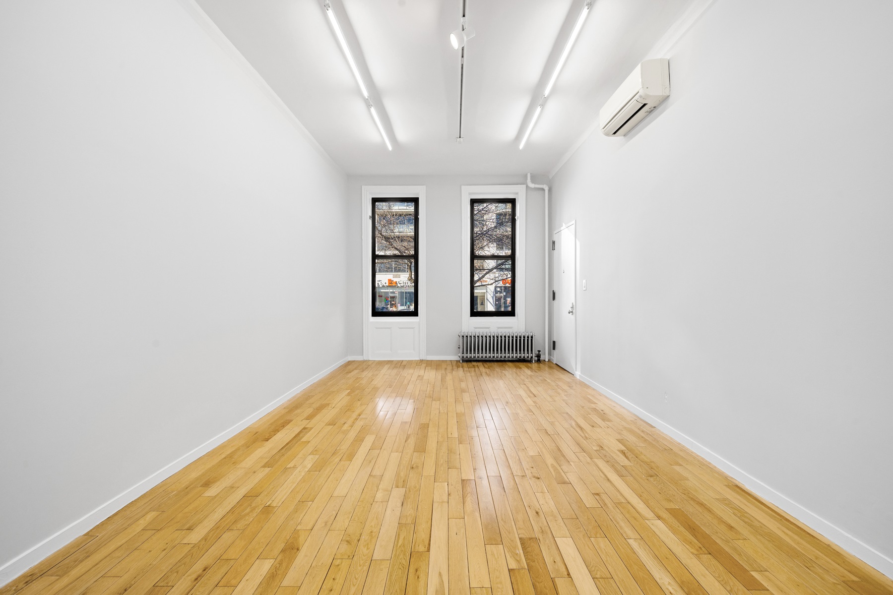 249 East Houston Street, Unit PARLOR Manhattan, NY 10002 - Photo 2 of 12 an empty room with wooden floor and windows