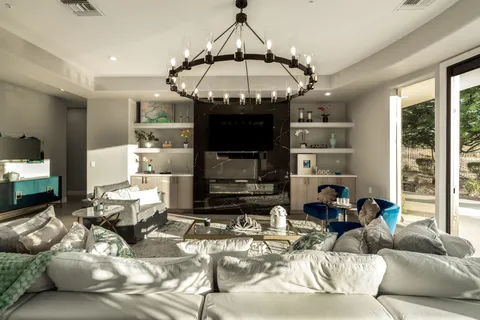 a living room with furniture kitchen view and a chandelier