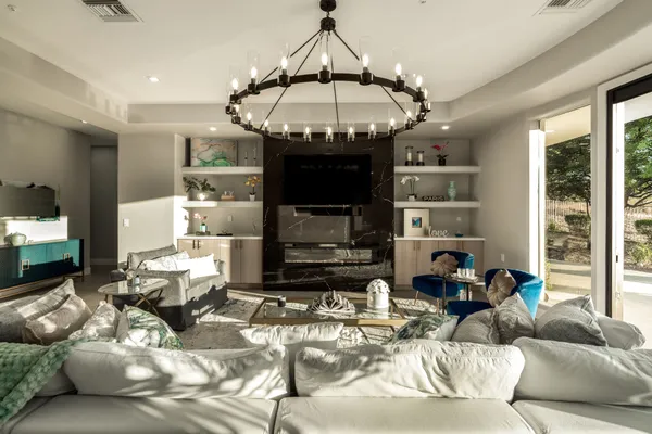 a living room with furniture kitchen view and a chandelier