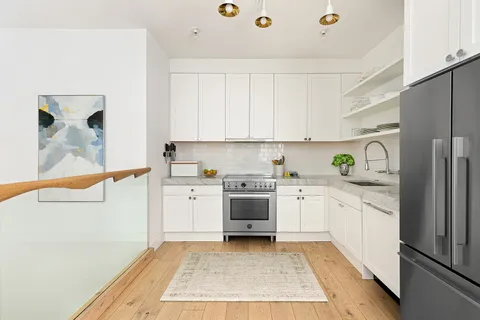 a kitchen with granite countertop a sink stainless steel appliances and white cabinets