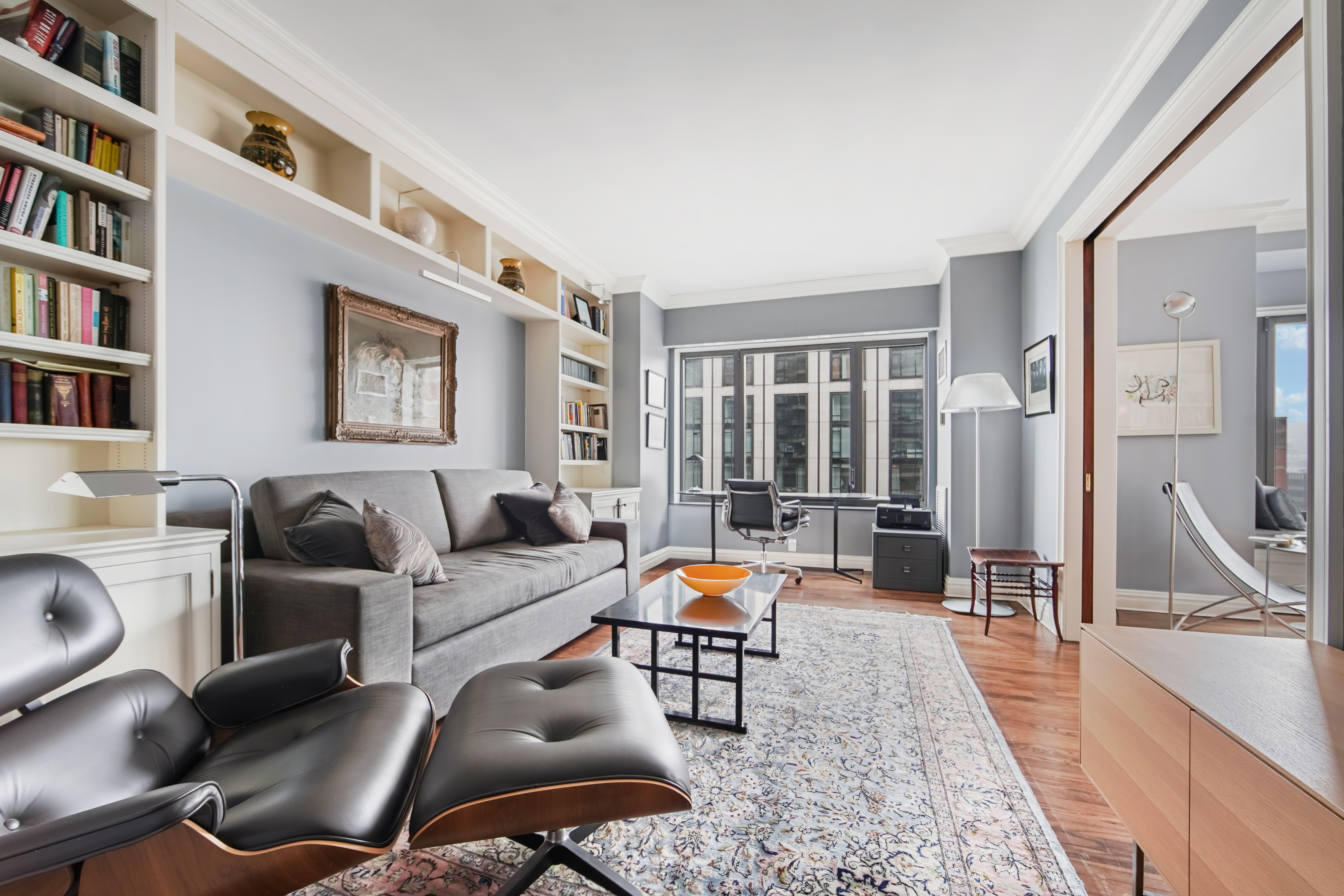 425 East 58th Street, Unit 29C Manhattan, NY 10022 - Photo 2 of 9 a living room with furniture a bookshelf and a large window