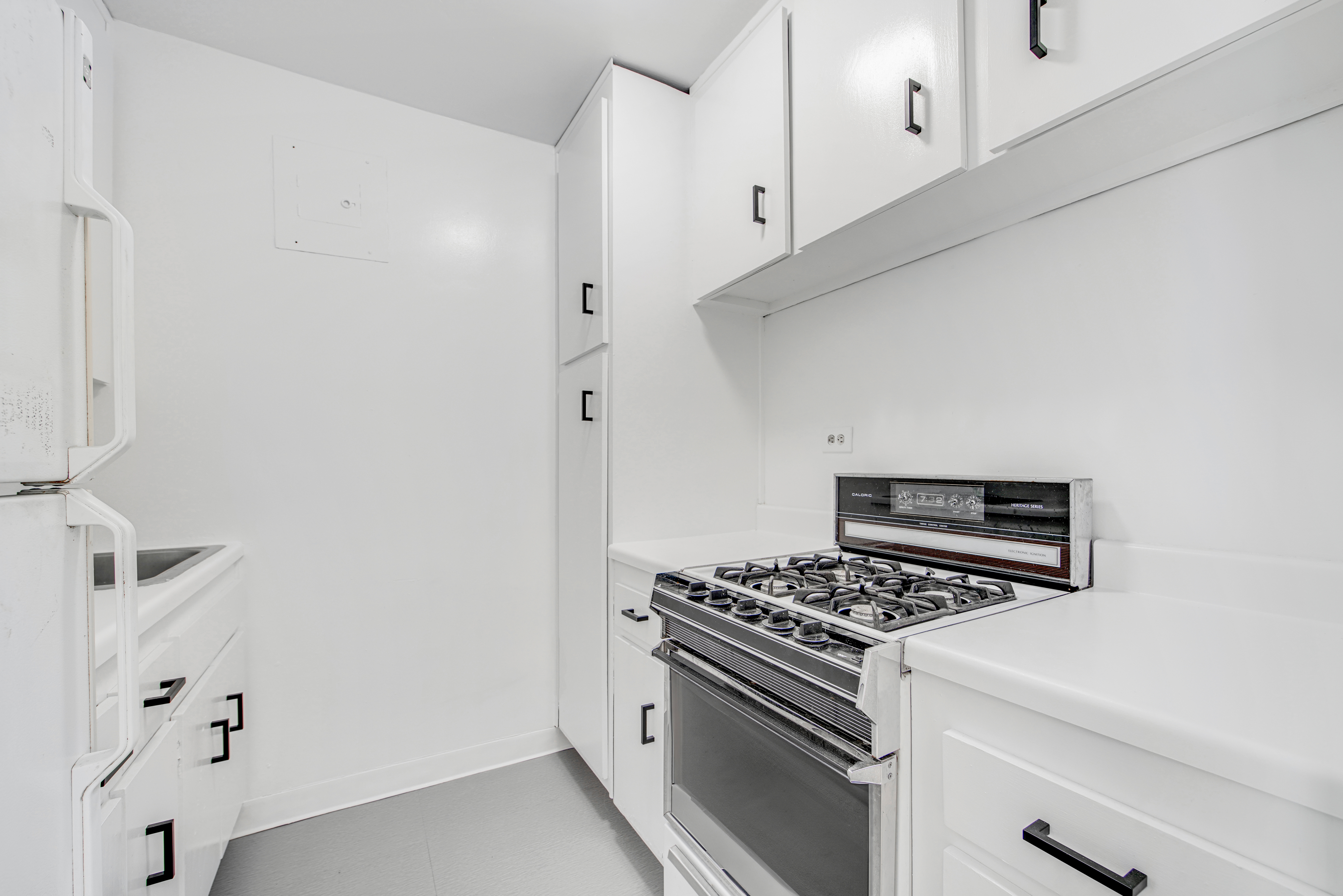 401 East 65th Street, Unit 10H Manhattan, NY 10065 - Photo 10 of 14 a kitchen with stainless steel appliances a stove and white cabinets