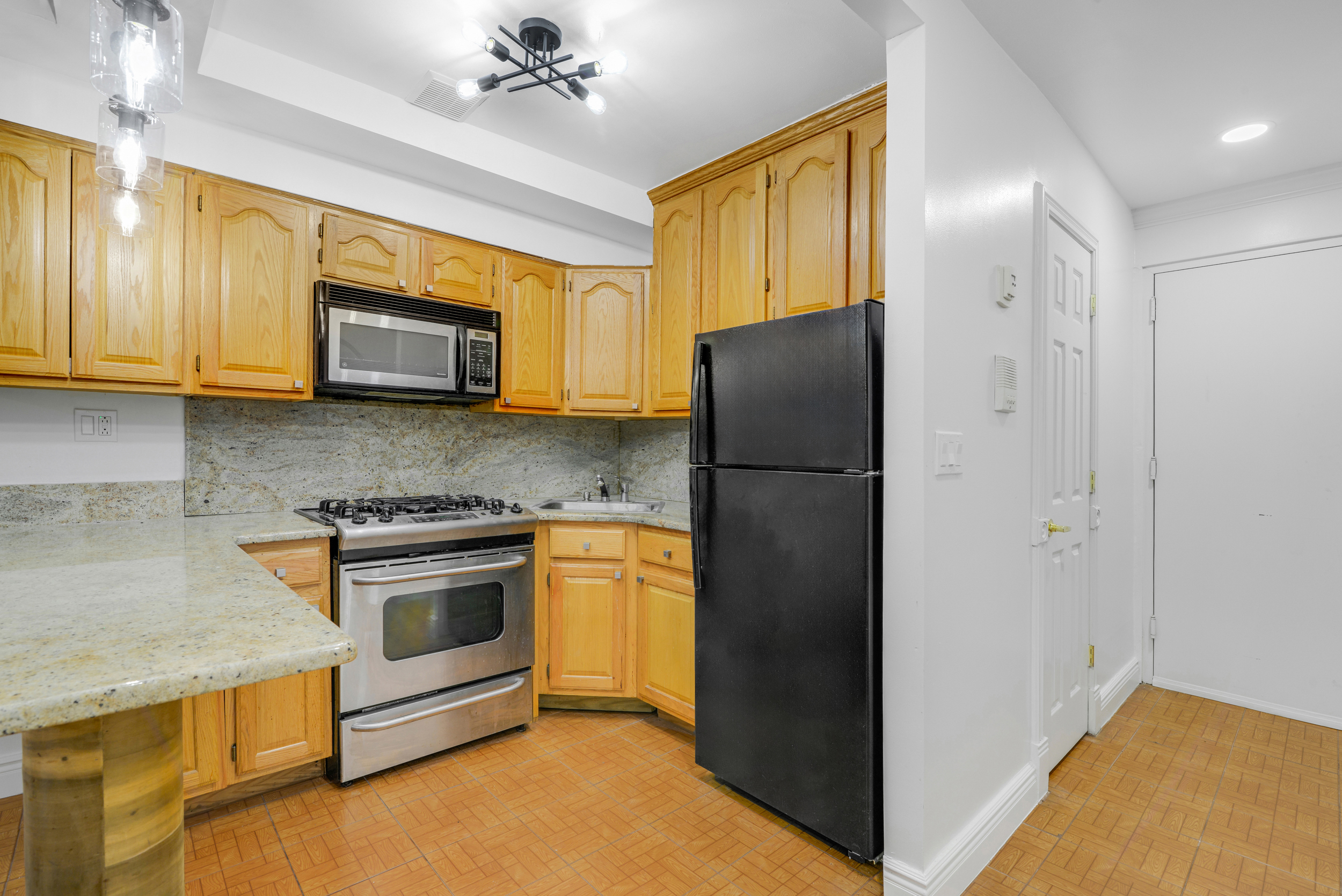 3 East 128th Street, Unit GARDEN Manhattan, NY 10035 - Photo 4 of 10 a kitchen with stainless steel appliances granite countertop a refrigerator and a stove top oven