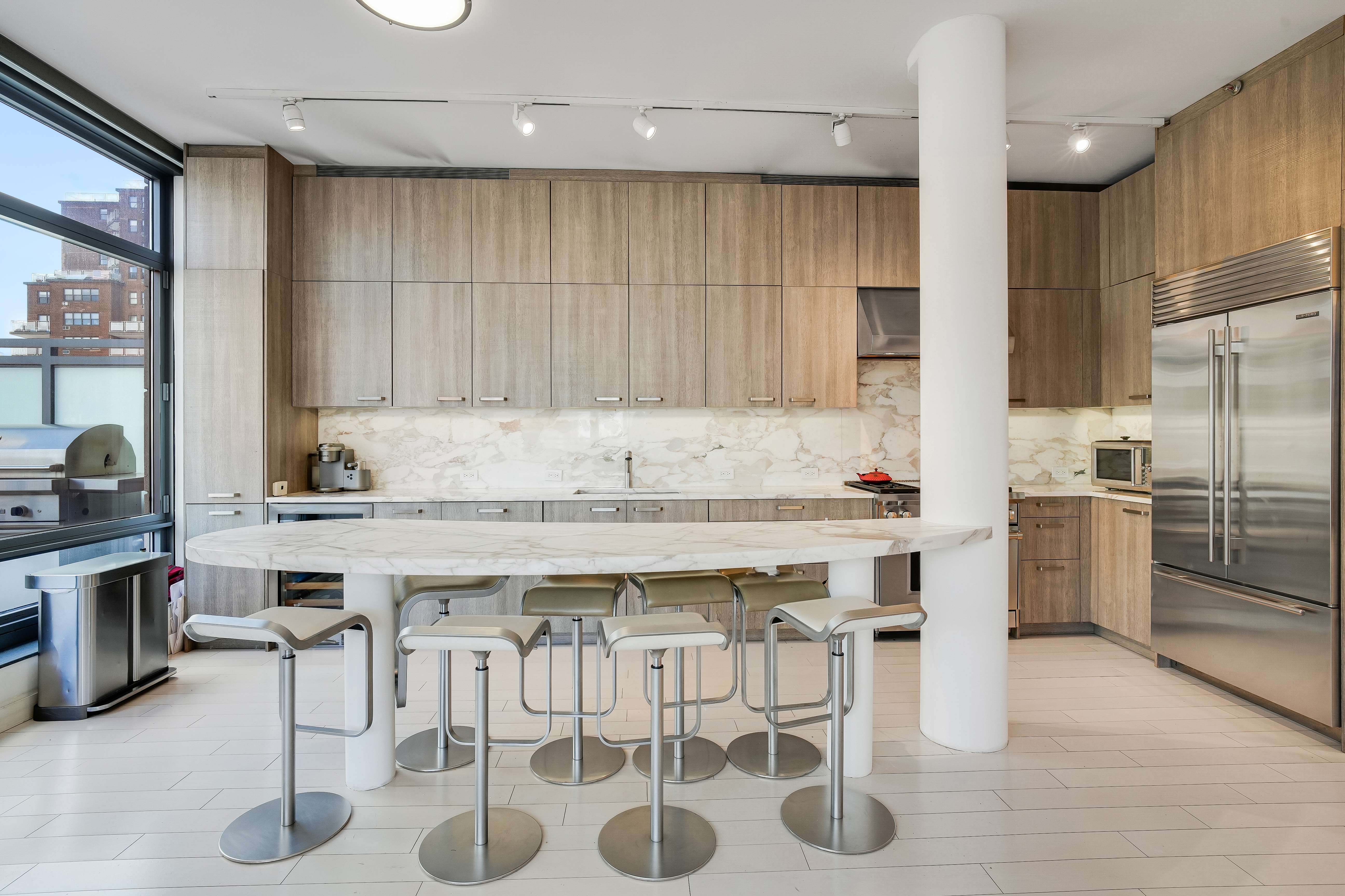 450 East 83rd Street, Unit 6B Manhattan, NY 10028 - Photo 7 of 25 a kitchen with stainless steel appliances granite countertop a table chairs sink refrigerator and microwave