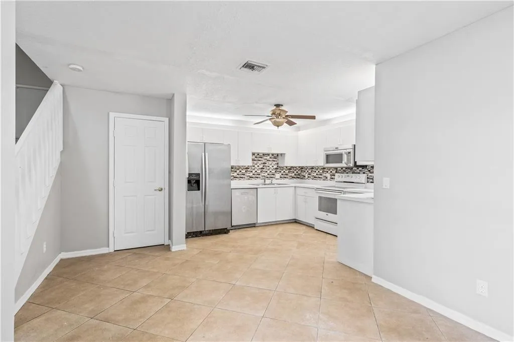 a large white kitchen with a sink stainless steel appliances and cabinets