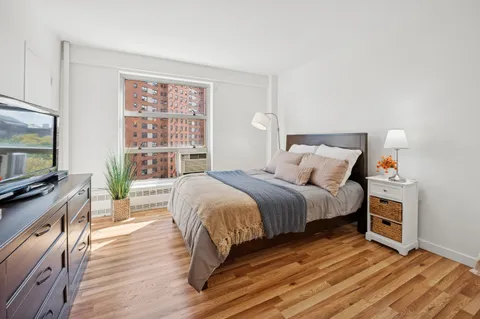 a spacious bedroom with a bed and wooden floor
