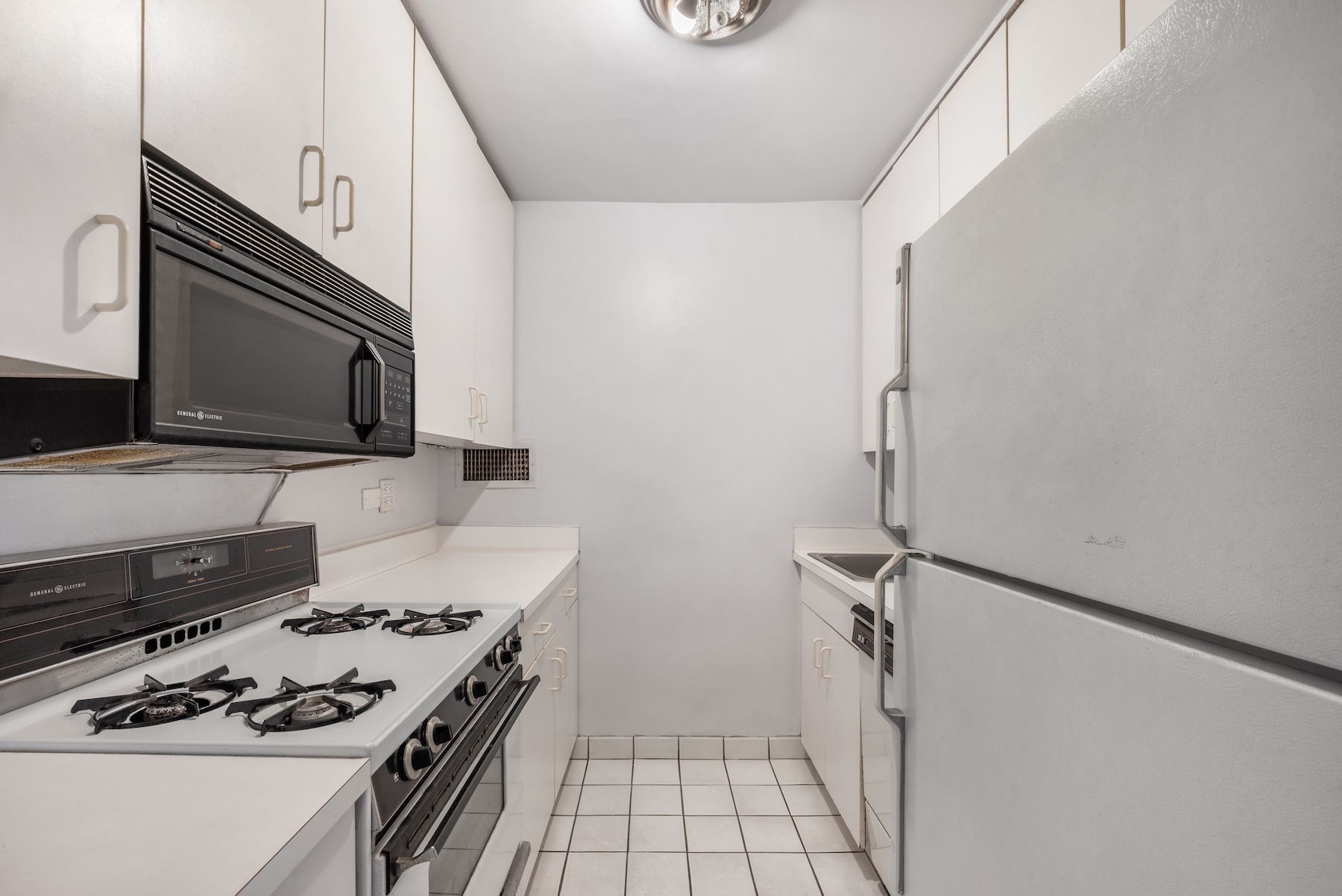 301 East 64th Street, Unit 4J Manhattan, NY 10065 - Photo 4 of 6 a kitchen with granite countertop a stove and a microwave