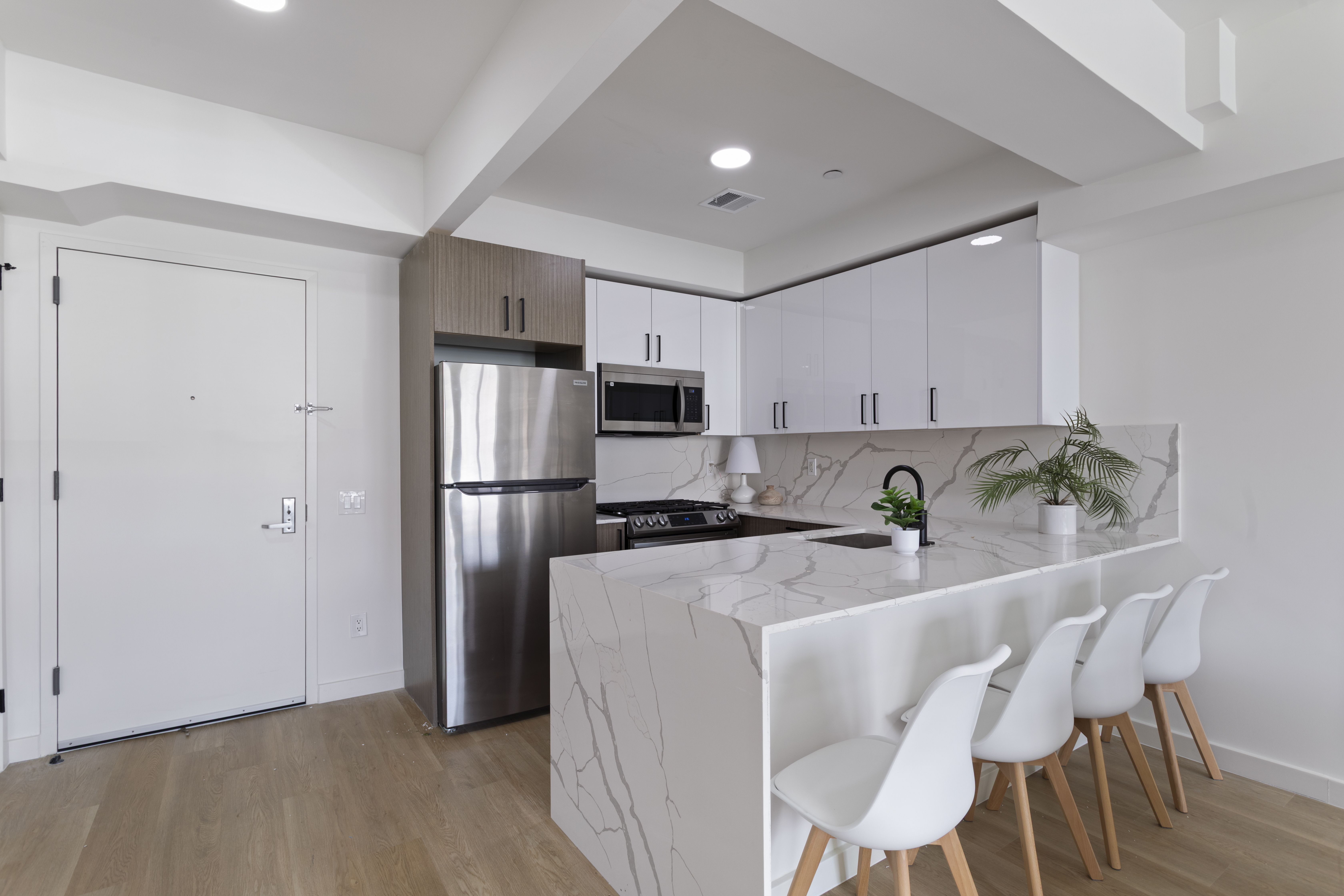 3112 Emmons Avenue, Unit 104 Brooklyn, NY 11235 - Photo 5 of 12 a kitchen with stainless steel appliances granite countertop a refrigerator a stove a sink dishwasher and white cabinets with wooden floor