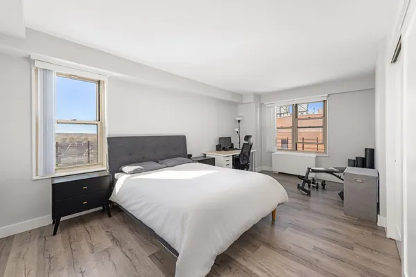 a bedroom with a bed windows and a wooden floor
