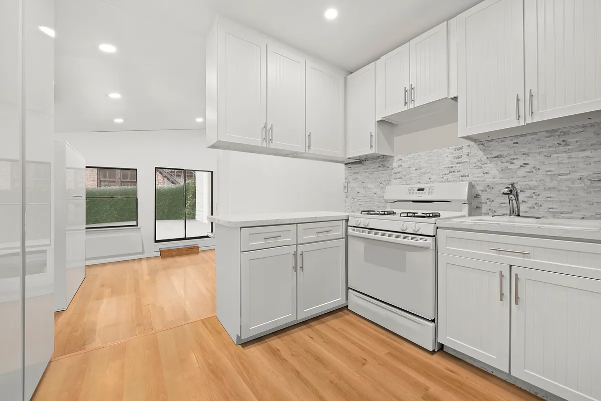 35 East 10th Street, Unit 2G Manhattan, NY 10003 - Photo 6 of 11 a kitchen with white cabinets and white appliances