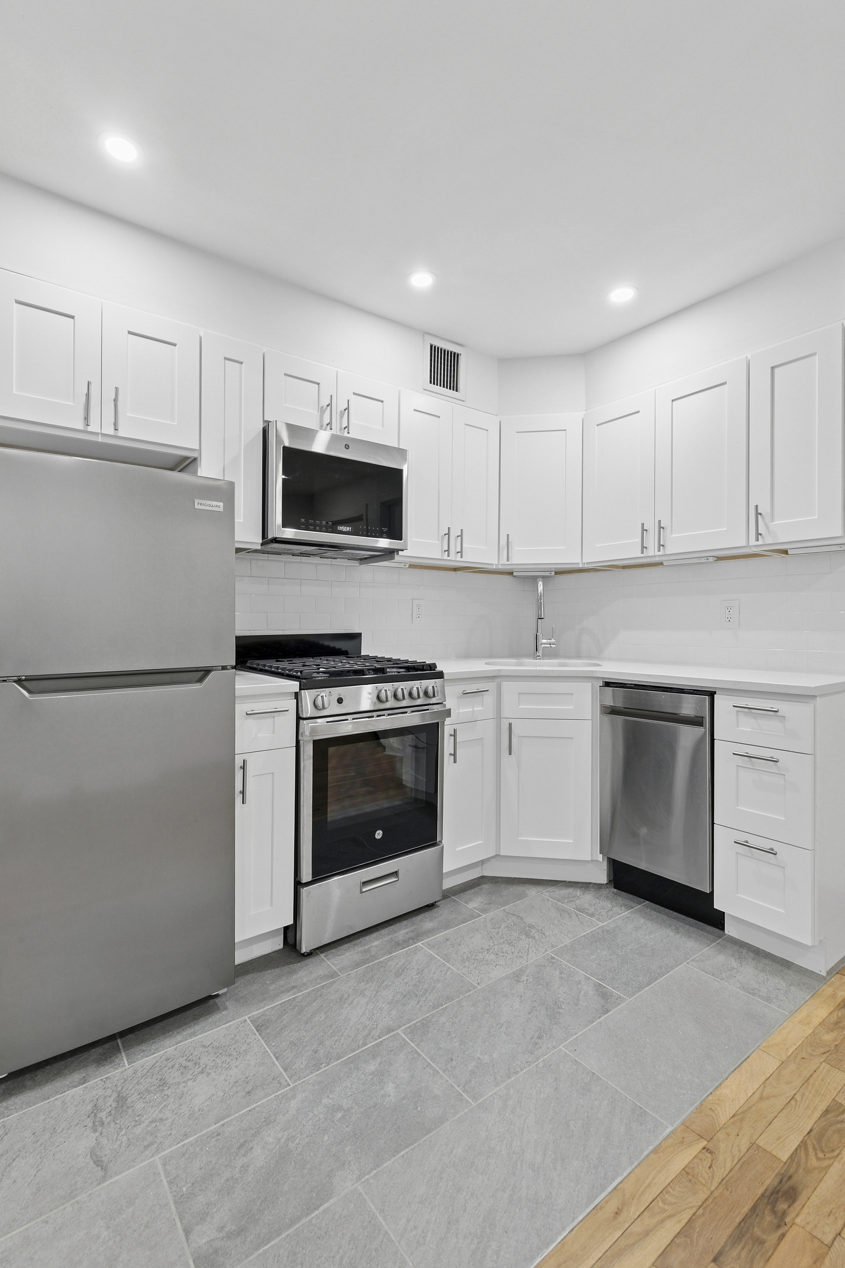 325 West 51st Street, Unit 1A Manhattan, NY 10019 - Photo 3 of 6 a kitchen with granite countertop white cabinets and stainless steel appliances