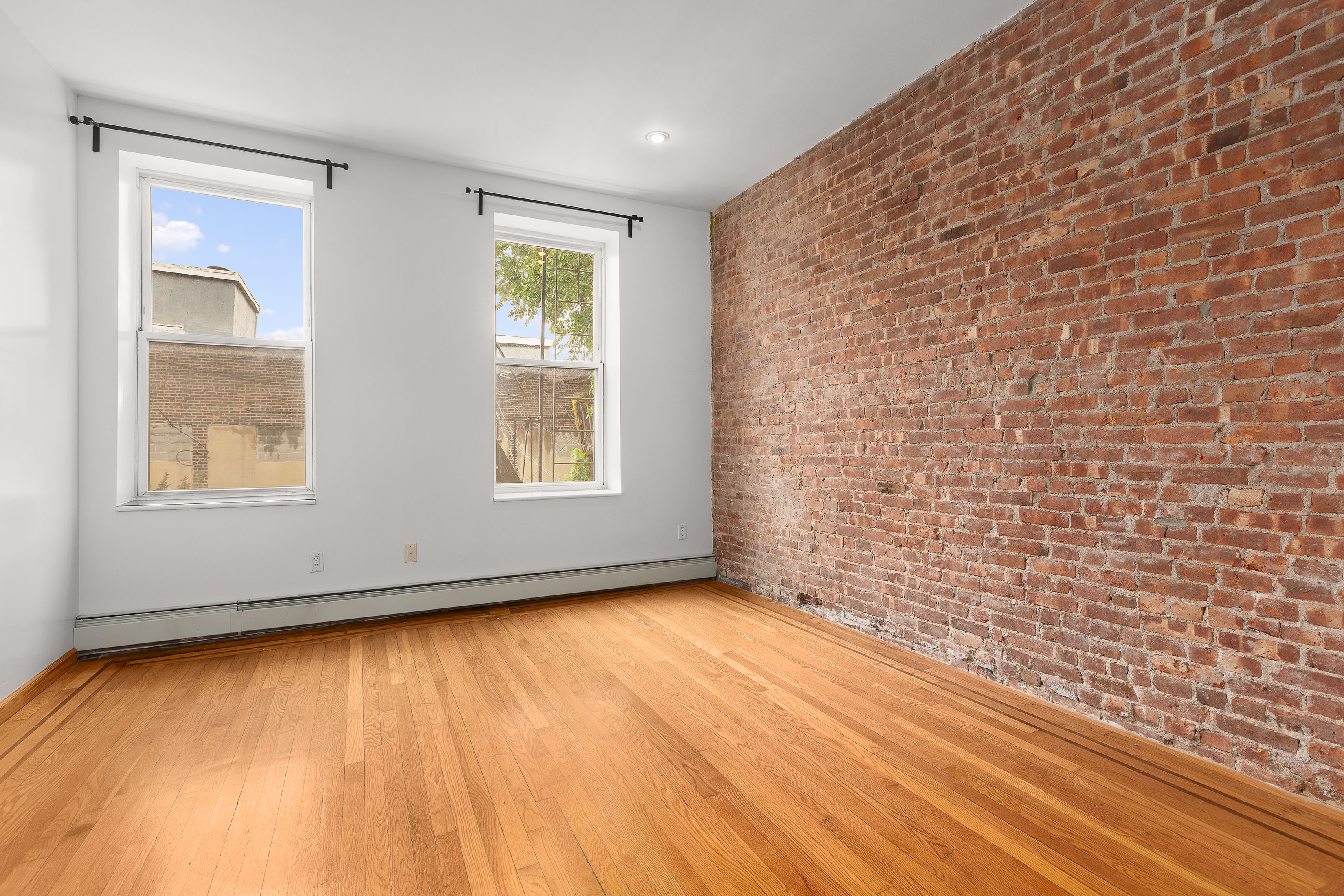 11-51 44th Drive, Unit 2 Queens, NY 11101 - Photo 3 of 6 a view of an empty room with wooden floor and a window