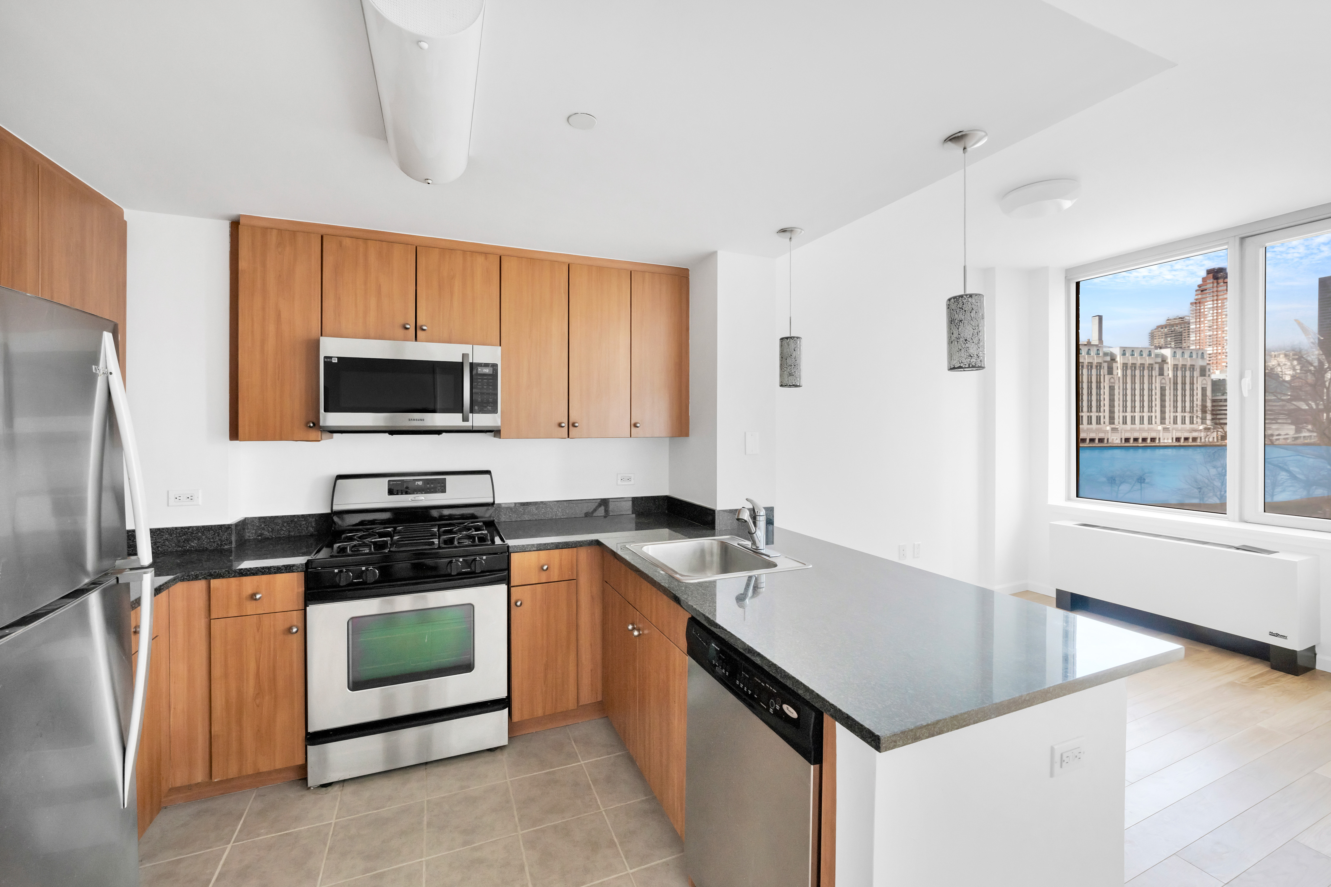 455 Main Street, Unit 5K Manhattan, NY 10044 - Photo 2 of 12 a kitchen with a sink a stove a microwave a counter space and cabinets