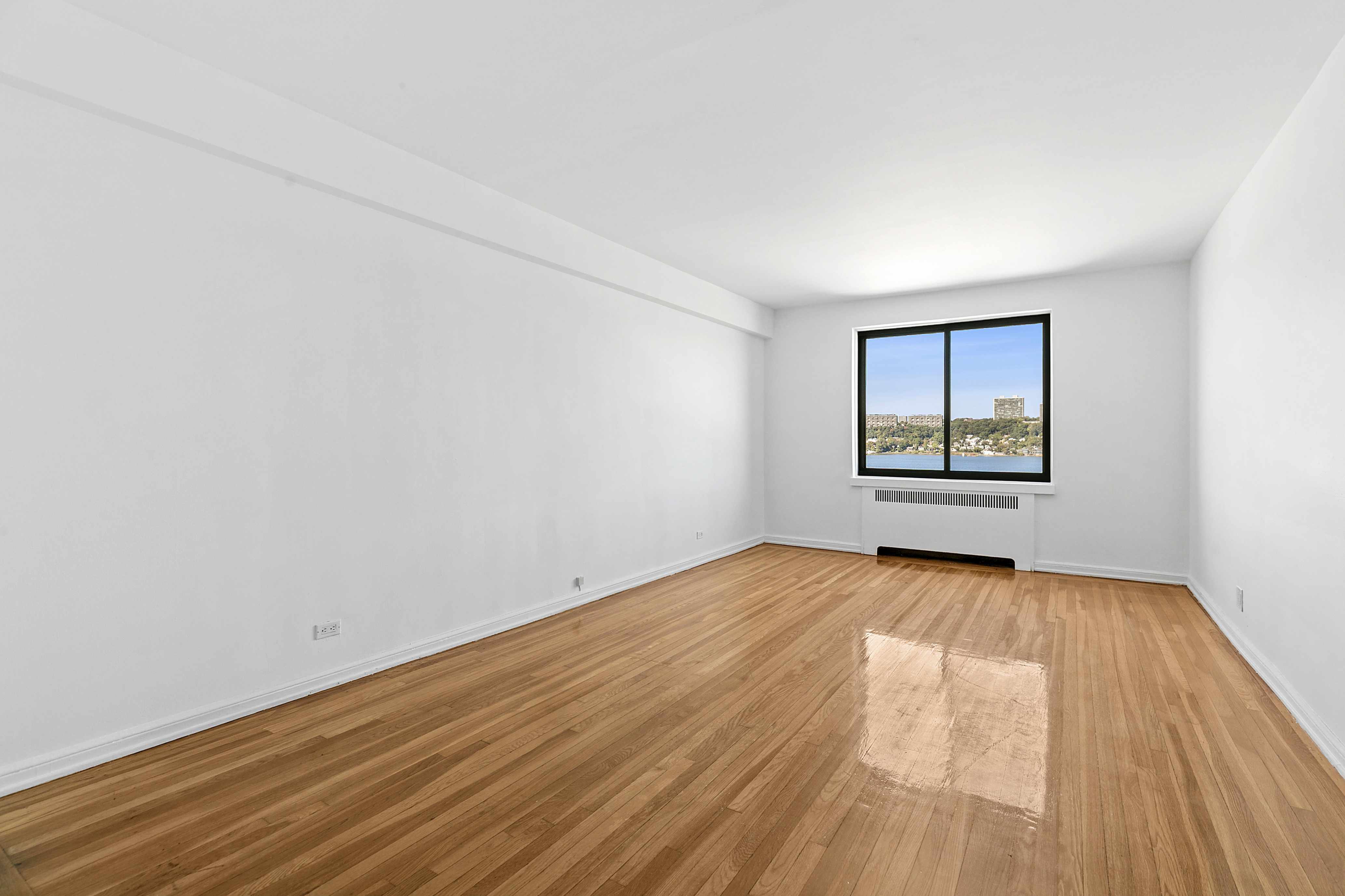 159-00 Riverside Drive West, Unit 4L70 Manhattan, NY 10032 - Photo 2 of 18 an empty room with wooden floor and windows