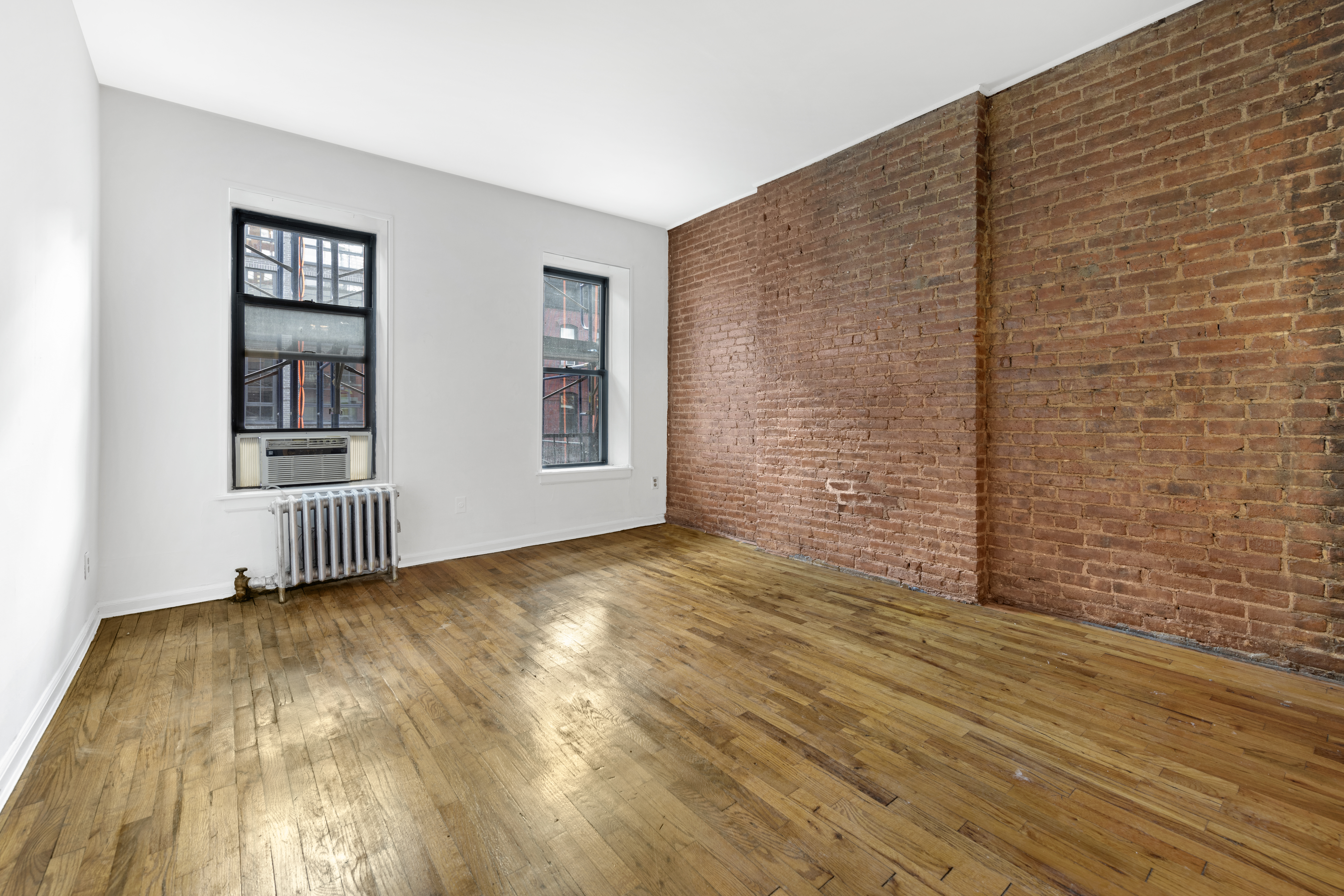 433 West 54th Street, Unit 20 Manhattan, NY 10019 - Photo 2 of 7 a view of an empty room with wooden floor and a window