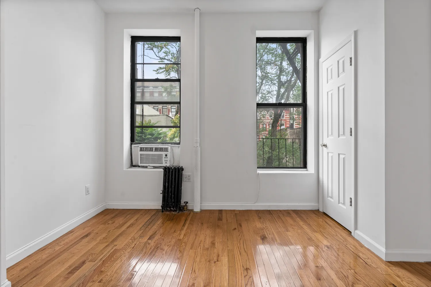 an empty room with wooden floor closet and windows