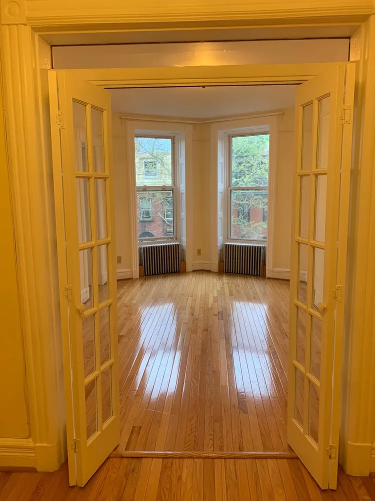 a view of empty room with wooden floor and fan