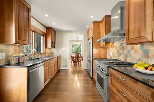 a kitchen with stainless steel appliances granite countertop a stove top oven a sink a dining table and chairs