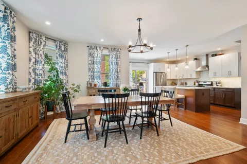 a view of a dining room and livingroom with furniture wooden floor a rug a rug a fireplace and a chandelier