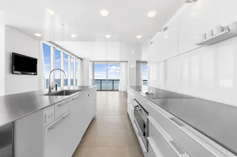 a large kitchen with a large counter top a sink a window and stainless steel appliances