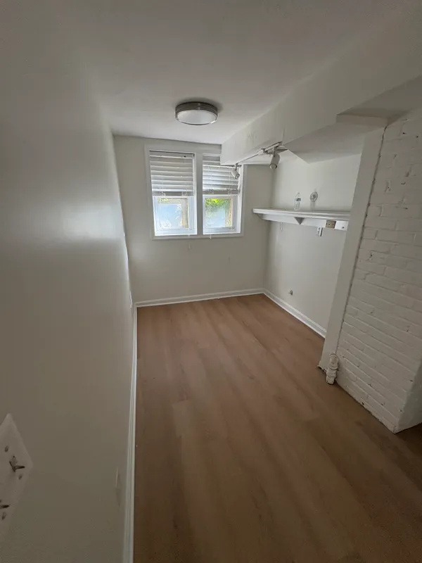 an empty room with windows and refrigerator