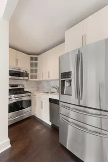 a kitchen with granite countertop white cabinets and stainless steel appliances