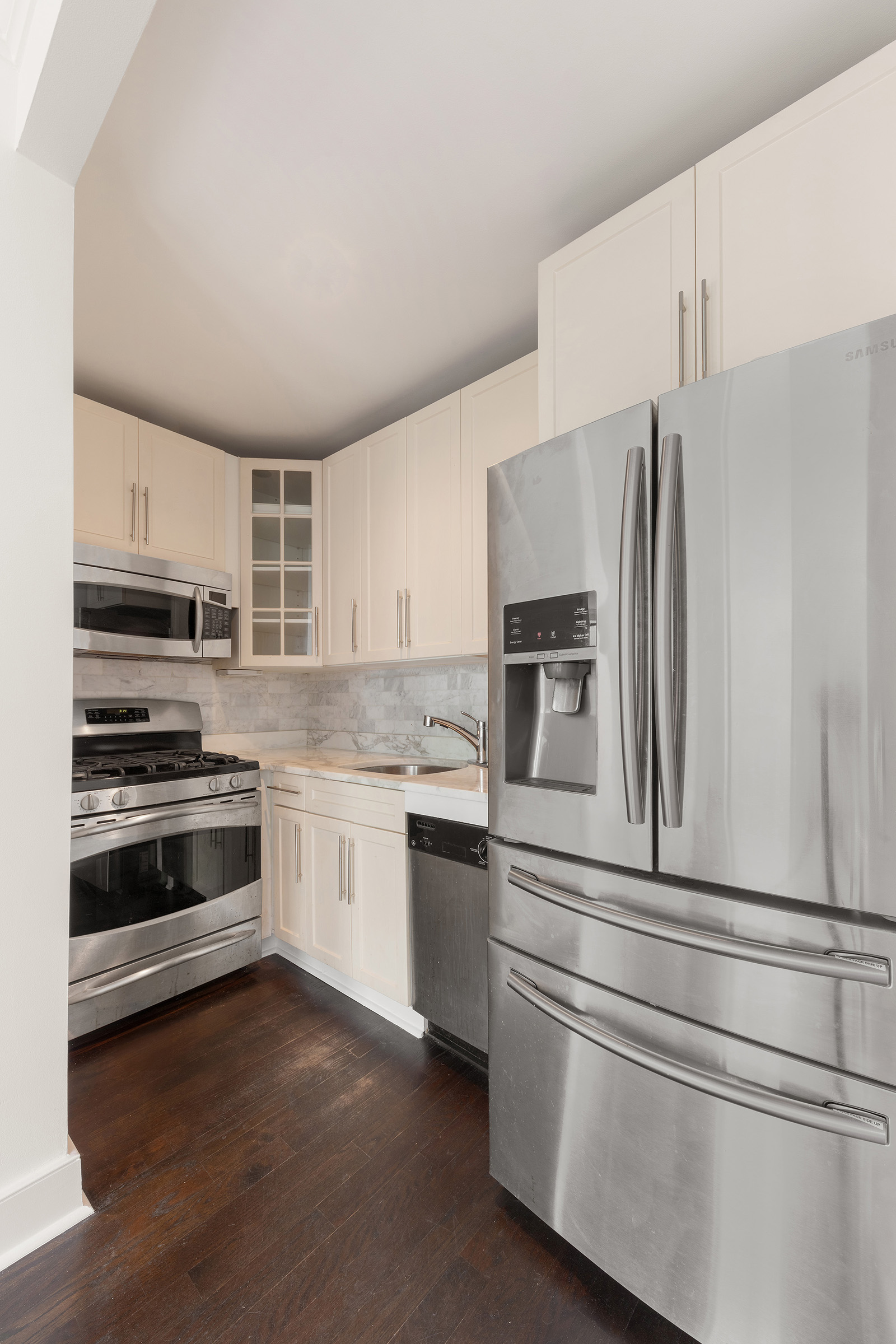 555 Lenox Avenue, Unit 3F Manhattan, NY 10030 - Photo 3 of 10 a kitchen with granite countertop white cabinets and stainless steel appliances