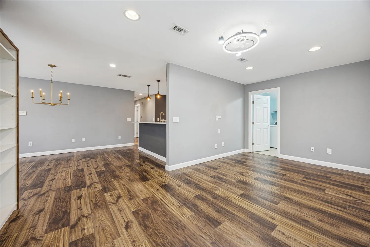 a view of an empty room with wooden floor and a ceiling fan