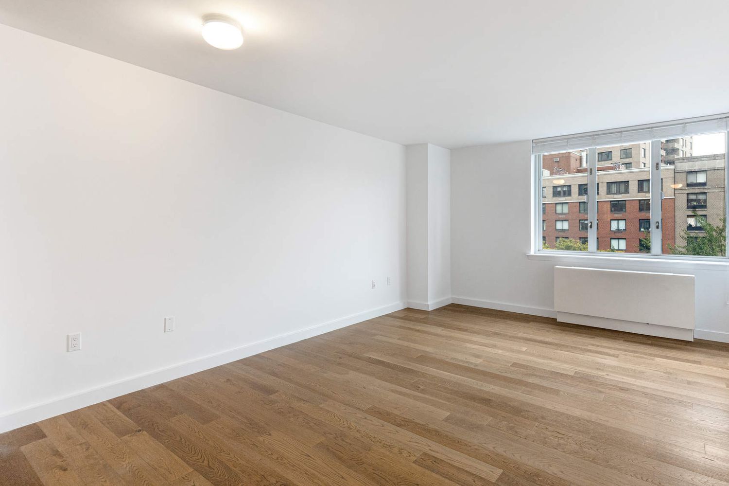 225 Rector Place, Unit 7M Manhattan, NY 10280 - Photo 3 of 13 an empty room with wooden floor and windows