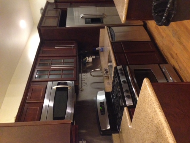 250 57th Street Brooklyn, NY 11220 - Photo 9 of 15 a kitchen with stainless steel appliances wooden cabinets and a stove top oven