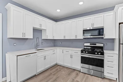 a kitchen with cabinets stainless steel appliances and a wooden floor