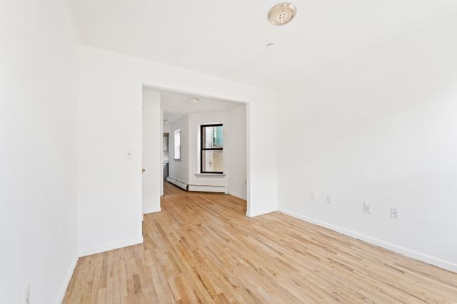 327 Pleasant Avenue, Unit 5B Manhattan, NY 10035 - Photo 5 of 5 a view of a room with wooden floor and white walls