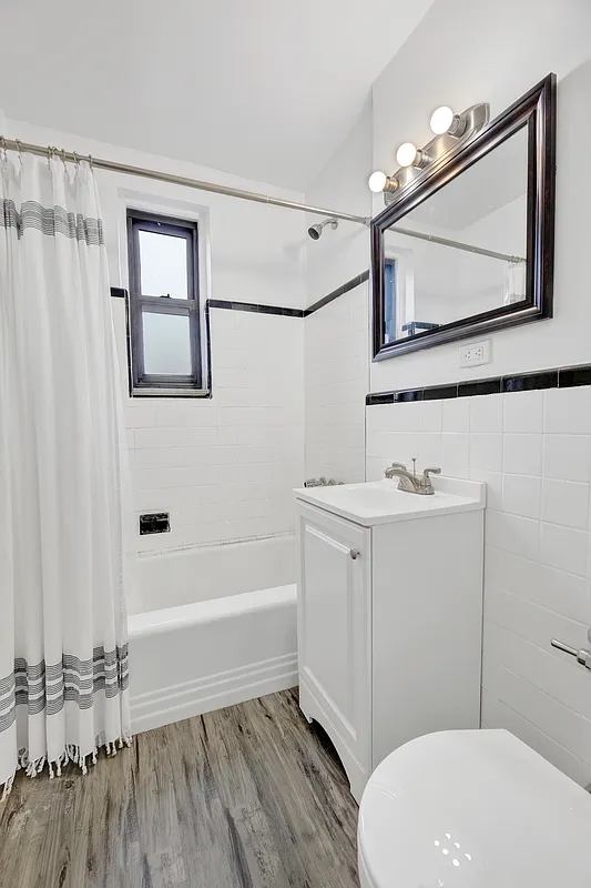 9040 Fort Hamilton Parkway, Unit 4G Brooklyn, NY 11209 - Photo 9 of 12 a bathroom with a sink a mirror a toilet and a bathtub