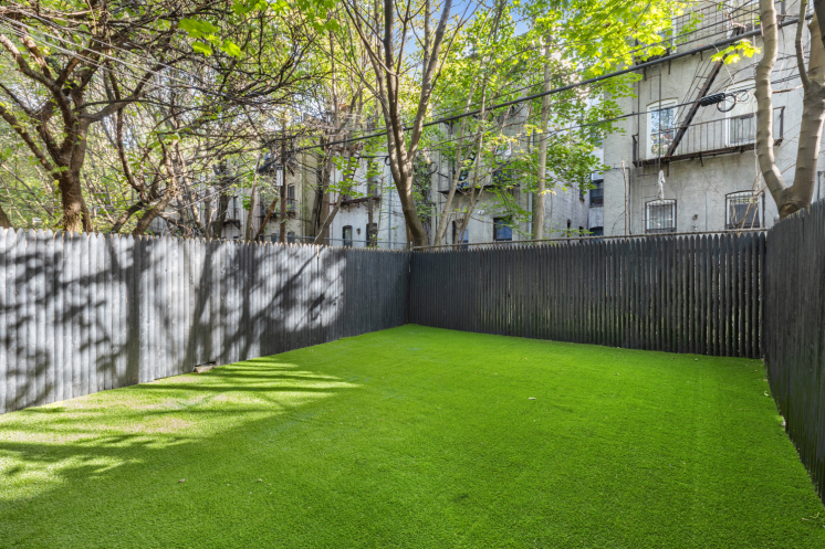 848 Macon Street, Unit PARLOR Brooklyn, NY 11233 - Photo 8 of 10 a view of a backyard with large trees and wooden fence