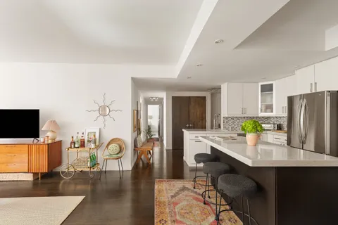 a kitchen with stainless steel appliances a dining table chairs and refrigerator