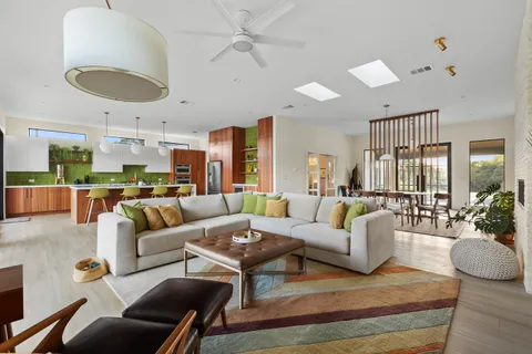 a living room with furniture kitchen view and a large window
